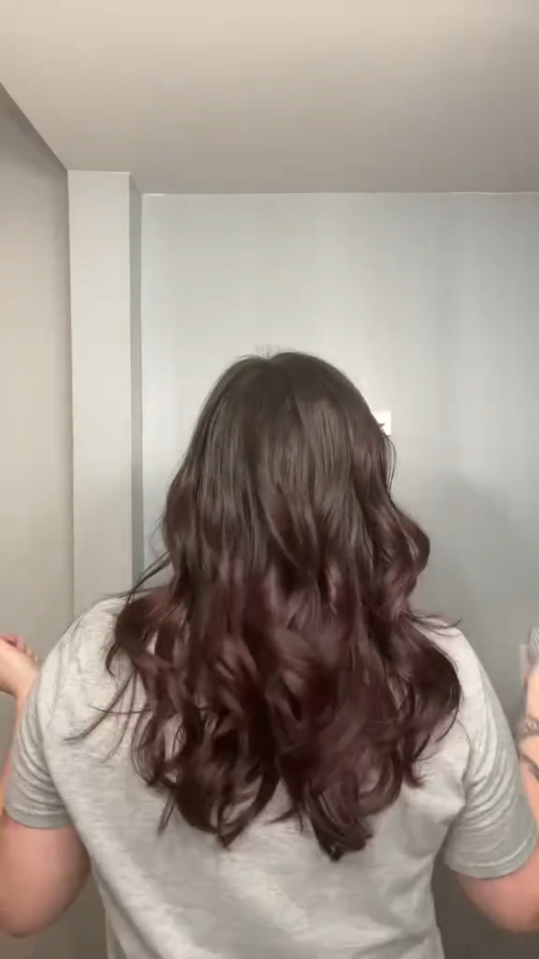 Person with long, wavy hair standing in front of a mirror.