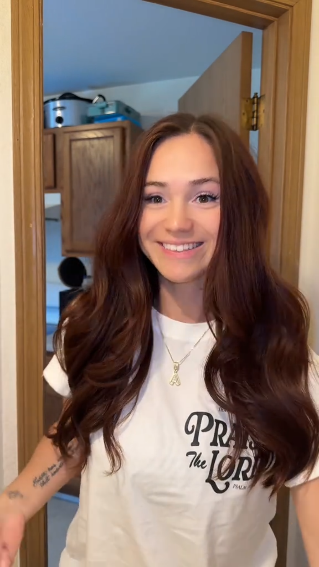 Woman wearing a white t-shirt with 'Praise the Lord' text in a home setting